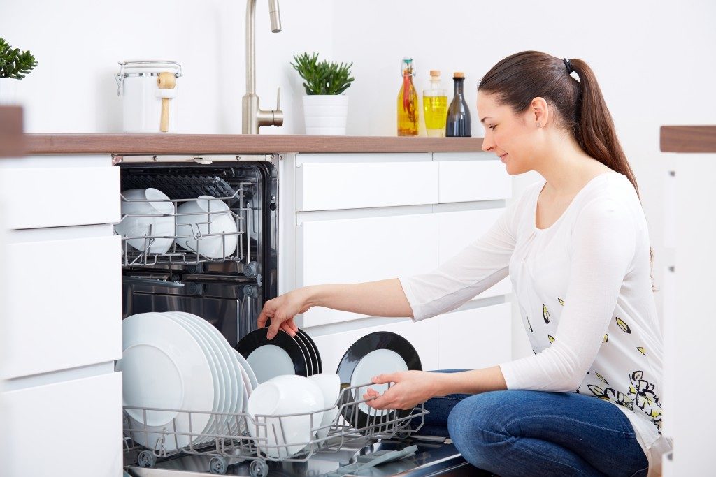 Woman getting plates from the dishwasher