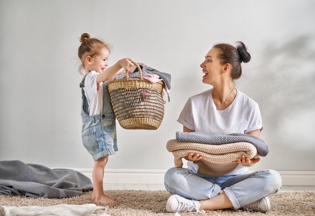 mother folding laundry with child