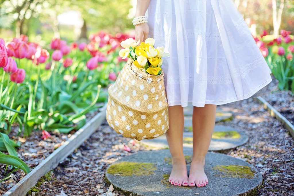 woman in dress on pavers amid flowerbed